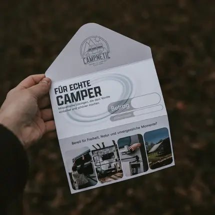 Campnetic Geschenkgutschein für Camper in Umschlag gehalten mit Aufschrift „Für echte Camper"