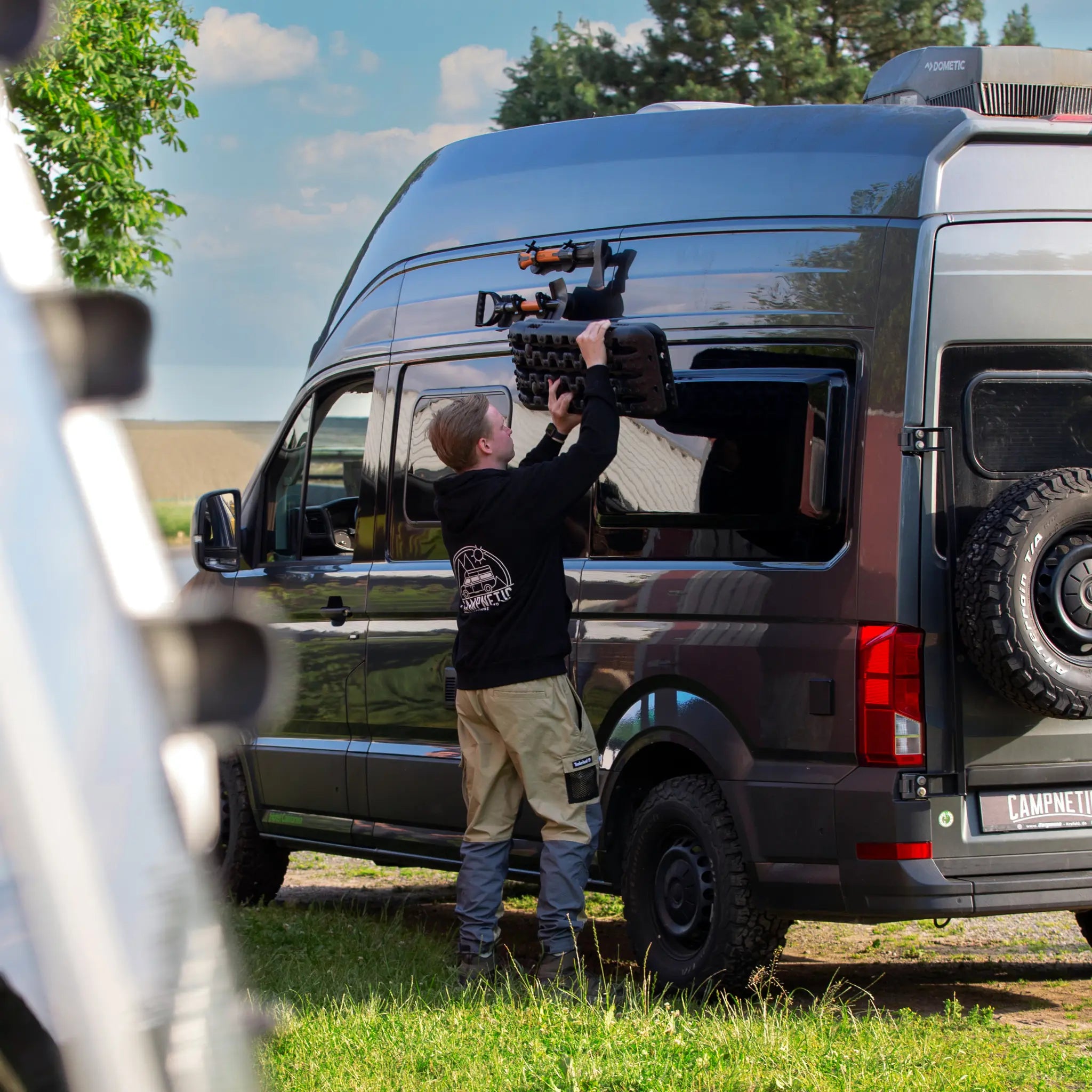 Person befestigt Campnetic Sandboard magnetisch an Mercedes Sprinter Campervan ohne Bohren